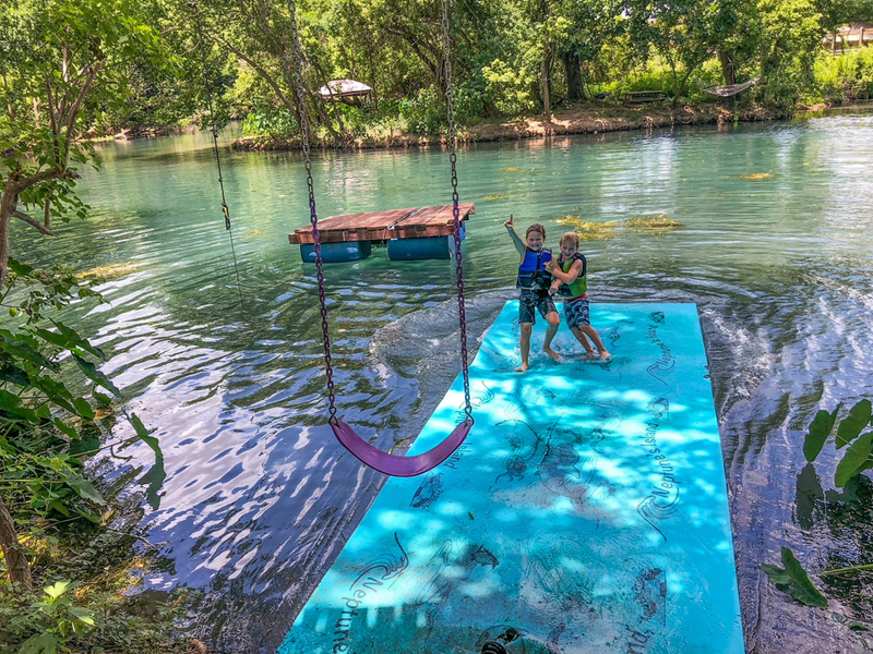 riverside area with swing and dock and 2 children posing