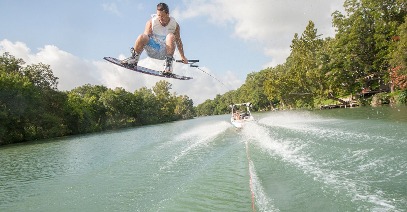 wakeboarder and boat driving down river