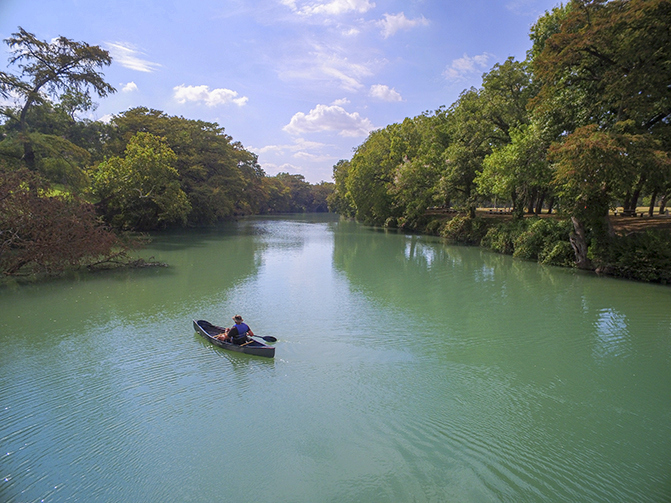 single kayak on river surrounded by forest