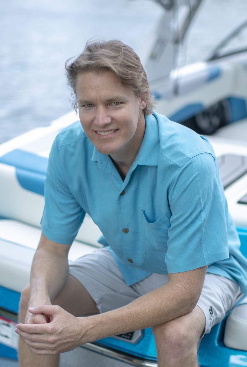 Hunter Croan, founder of The Lakefront Group, seated on a wake boat on the water